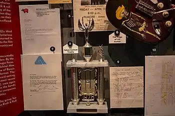 The trophy given to U2 for winning the 1978 Limerick Civic Week music talent contest. To the right are handwritten lyrics for the song "Out of Control", which is featured on Three.