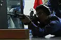 Seaman Shusaku Okamura, a Fleet Air Wing 31 air crewman, snaps into the prone position and aims down range during rifle re-qualification and familiarization training at the Indoor Small Arms Range here Dec. 2