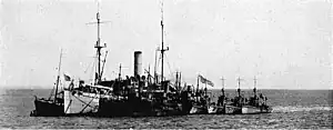USS SC-48 (right center, under the large American flag) anchored aport of Panther and several naval trawlers at Kirkwall Harbor, Orkney Islands, in 1919. Sister ships SC-328, SC-38, and SC-181 are aport of SC-48.
