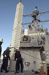 A Tomahawk missile canister being loaded into a VLS aboard the Arleigh Burke-class destroyer USS Curtis Wilbur