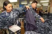 YN1 Latricia Perkins (left), assigned to the Administration Department at Naval Air Facility Atsugi, Japan, sorts through a pile of the new Navy Working Uniforms.