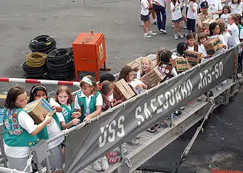 Girl Scouts and Brownies from two troops in Singapore pass Girl Scout cookie boxes up the brow of the rescue and salvage ship USS Safeguard (ARS 50) as part of Operation Thin Mint.
