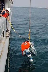 The ADS 2000 suit is lowered into the sea from the side of a ship