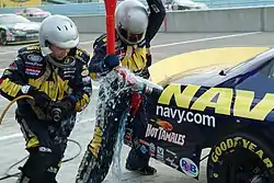 Fuel spills from the gas tank as pit crew members in their PPE