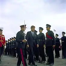 John Fitzgerald Kennedy, escorted by Governor and Commander-in-Chief of Bermuda, Major-General Sir JA Gascoigne, KCMG, KCVO, CB, DSO, DL, and Major JA Marsh, DSO, the Officer Commanding the Bermuda Militia Artillery, inspects a Bermuda Rifles guard in 1961, four years before the units amalgamated