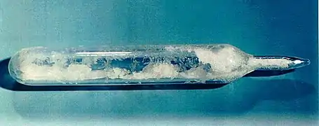 test-tube like glass container, with pointy sealed end, filled with white crystals