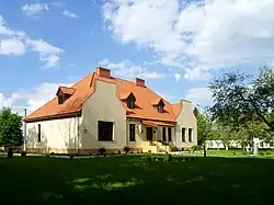 Photo of a large concrete house with a red roof and large lawn