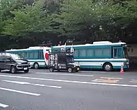 An uyoku gaisensha passing two Tokyo Metropolitan Police Department riot buses
