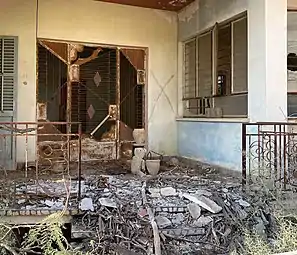 An abandoned house in Varosha;  in front of the home is a frayed teddy bear.