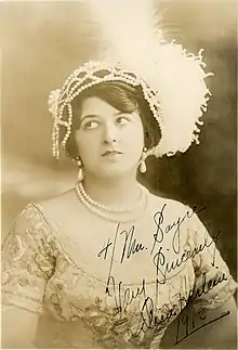 A young white woman with dark hair, wearing an elaborate beaded and plumed headpiece