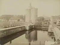 The lock with 'het landje van top' on the left and the Drommedaris around 1870. The wide bridge and the house next to the bridge with tilted covered balconies are still present on this photo. It is the oldest picture of the Drommedaris.