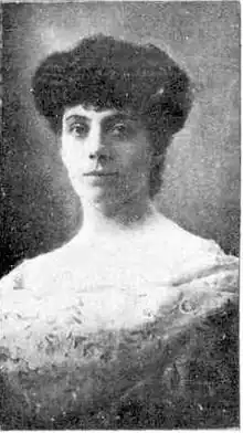Upper body black-and-white photo of a woman. She has dark hair raised atop her head. She wears a formal gown.