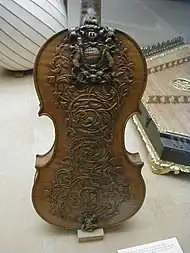 Scrollwork and the royal arms of the Stuarts on the back of a violin, English about 1680