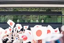 A group of people wave Japanese flags at the Imperial Palace.