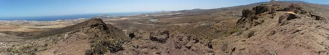 View towards the south-east from the Four Doors site.On the coast, almost in line with the forefront left peak: the Punta de Gando and Gran Canaria airport just in front of it.