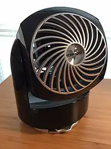 This is an image of a Vornado Brand Table Fan. Model Type FLIPPI V6. It is small and black with a silver fan face and black shiny body.
