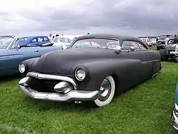 A mild kustom 1949 Merc in progress. Note the deep chop, dagmars, 1955 Cadillac grille, wide whites, frenched headlights, Appletons, and vee-butted windshield.