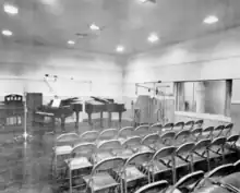 Radio studio with microphones, two grand pianos and folding chairs for an audience