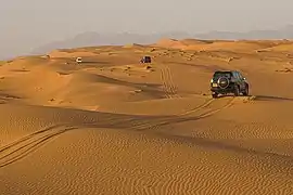 Vehicles on the dunes near the Eastern Hajar Mountains