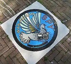 War Pigeon Spy, artwork in the memorial manhole-series Friendly Fire (at Kraaienplein)