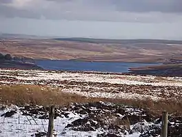A shot across snowy moorland of an upland lake