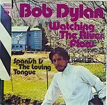 A 7-inch single cover showing Bob Dylan in front of a field. The words "Bob Dylan", "Watching The River Flow", and "Spanish Is The Loving Tongue" appear over the picture.