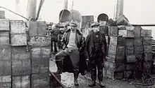 Salvage men photographed among the salvaged cases of whisky