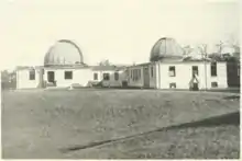 black and white image of a white building topped by two closed telescope domes