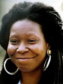 Headshot of Whoopi Goldberg. She has thick black hair and is wearing large hoop earrings.