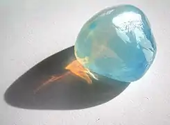 Tyndall effect in an opalite:it scatters blue light making it appear blue from the side, but orange light shines through.opal is a gel in which water is dispersed in silica crystals