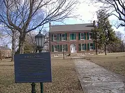 A two-story mansion with a historical marker in the foreground