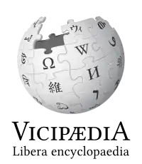 The logo of Latin Wikipedia, an incomplete sphere made of large, white, jigsaw puzzle pieces. Each puzzle piece contains one glyph from a different writing system, with each glyph written in black. The Latin Wikipedia wordmark displays the name Vicipædia, written in all caps. The V and the A are the same height and both are taller than the other letters which are also all the same height.
