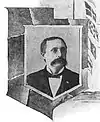 Head and shoulders of an otherwise-cleancut man with an enormous mustache, in circa-1900 formal dress.
