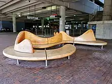 A wavy wooden bench inside a parking garage