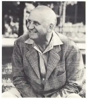 William M. "Skipper" Beals seated on the lawn in front of the original Homestead Building on the Leelanau for Boys campus ca. 1940