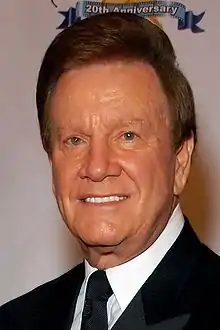 Television host Wink Martindale, wearing a black suit and tie.