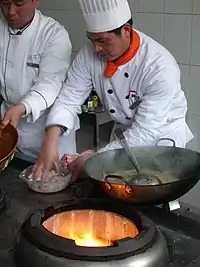 Preparing food over a modern gas-fired, pit-type wok stove
