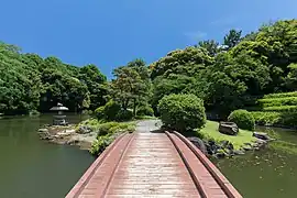 Wooden footbridge in Shinjuku Gyoen National Garden, a sunny day with blue sky