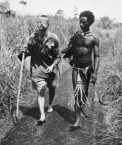 An Australian soldier, Private George "Dick" Whittington, is aided by Papuan orderly Raphael Oimbari, near Buna on 25 December 1942. Whittington died in February 1943 from the effects of bush typhus
