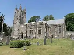 Stone building with square tower. In the foreground are gravestones