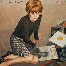 A painting of a woman seated on the floor, surrounded by LPs