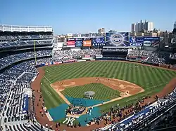 A baseball stadium with blue seats and buildings visible in the background.