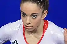 An image of a Caucasian teenage girl. She is wearing a white leotard.