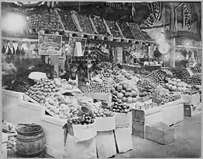 Stand 253 (B Street Wing) - Young boy tending freshly stocked fruit and vegetable stand at Center Market on February 18, 1915