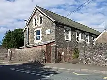 Grey stone chapel-style building with white window surrounds