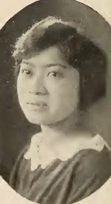 A young Japanese woman, wearing a dark top with a white lace collar