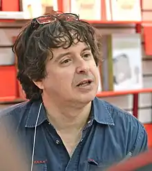 close-up of Yves Pelletier wearing a dark blue shirt, looking left of camera and appearing to speak