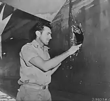 Image 361st Lt. Louis Zamperini, peers through a hole in his B-24D Liberator 'Super Man' made by a 20mm shell over Nauru, 20 April 1943 (from History of Tuvalu)