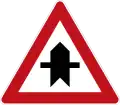 Dangerous intersection with priority indication (for the next intersection only). Different variants of the sign can be used on both priority- and non-priority roads. Each sign has the thicker line indicating the road or direction that has priority with the viewer's own direction being from the bottom of the sign.