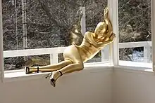 Woman in gold zentai and black heels posing on a windowsill